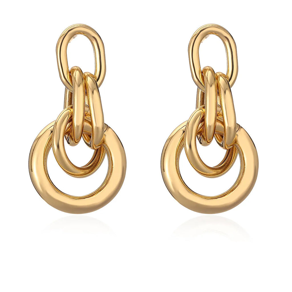 A pair of gold-colour geometric earrings with an irregular, high-profile design on a white background.