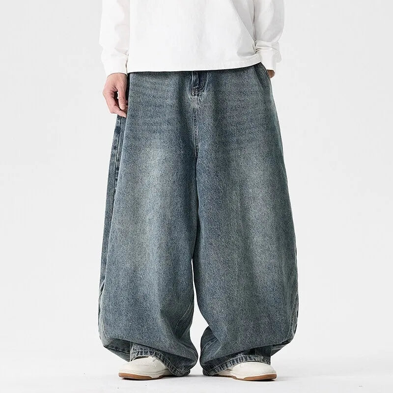 Men's plus-size baggy blue jeans with a wide leg and straight hem on a casual background.