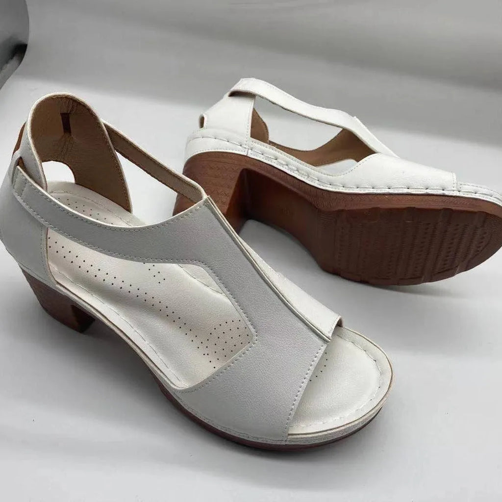 Women's white peep toe wedge sandals with Roman-style buckle ankle straps on a low heel.