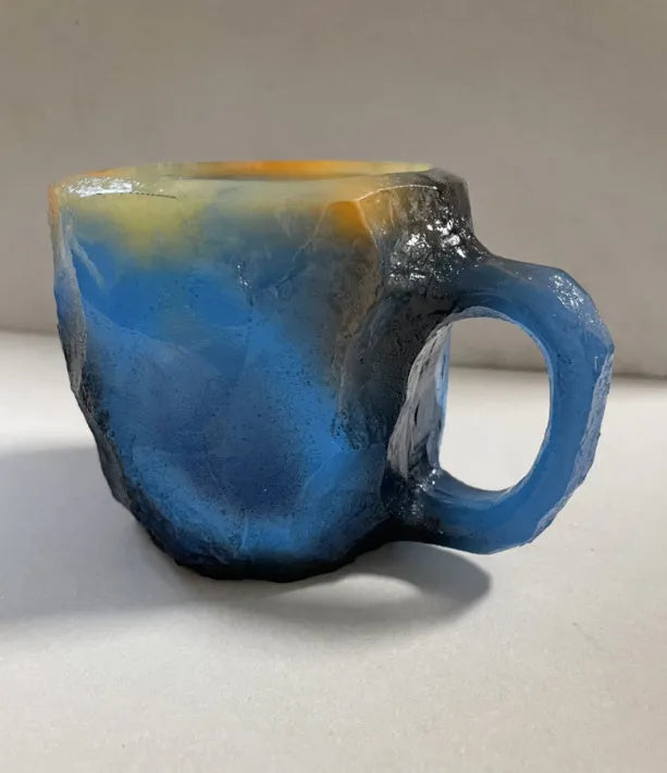 Purple and blue resin coffee mug with crystal texture and handle on wooden table
