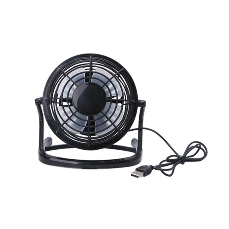 Small black USB desk fan with adjustable angle on wooden desk next to laptop