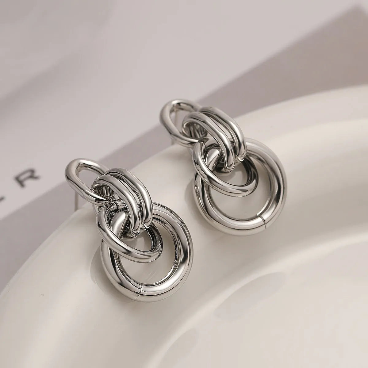 A pair of gold-colour geometric earrings with an irregular, high-profile design on a white background.