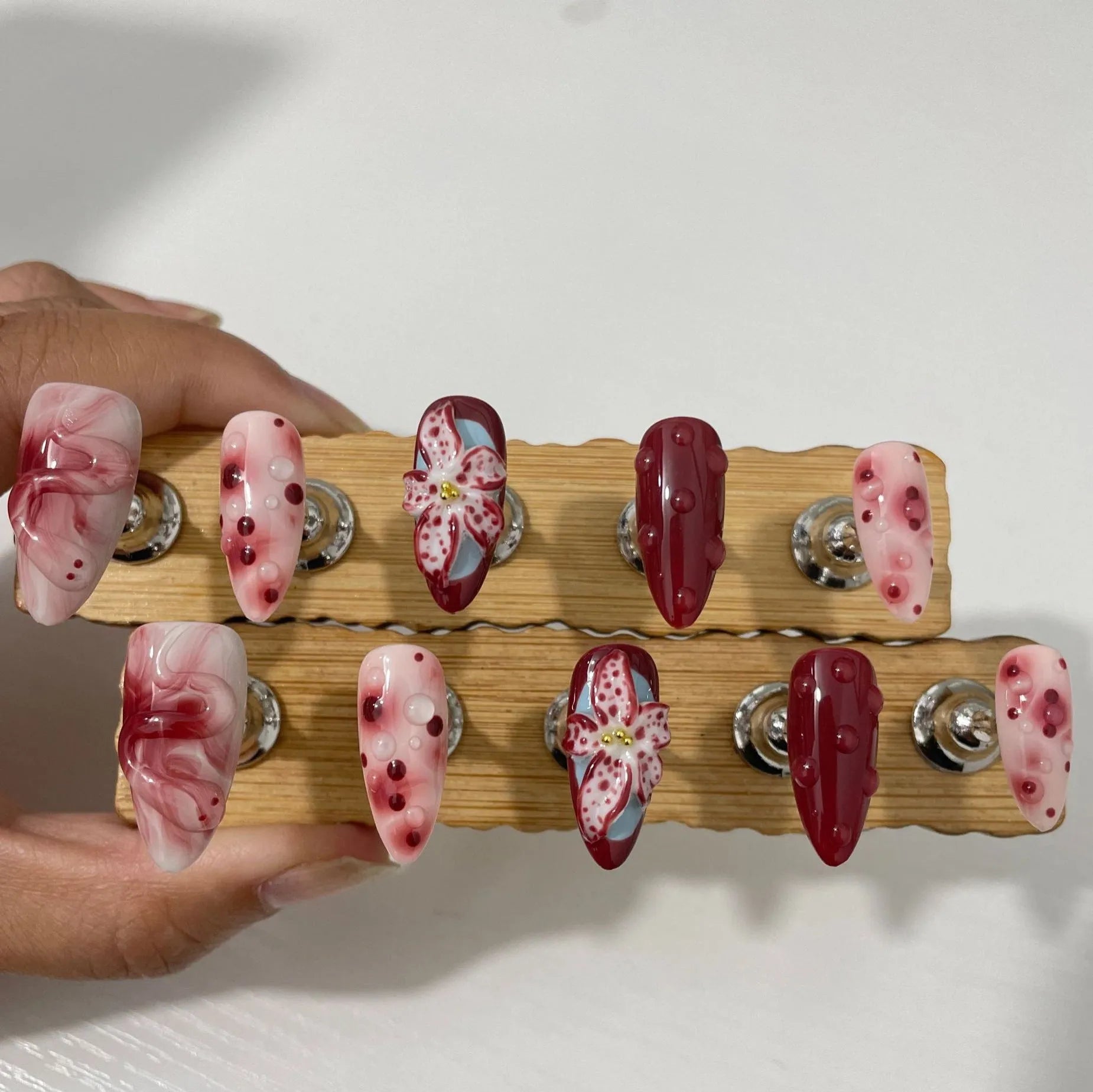 Set of almond-shaped false nails with hand-painted 3D rose and starry sky designs, showing ultra-thin edges.