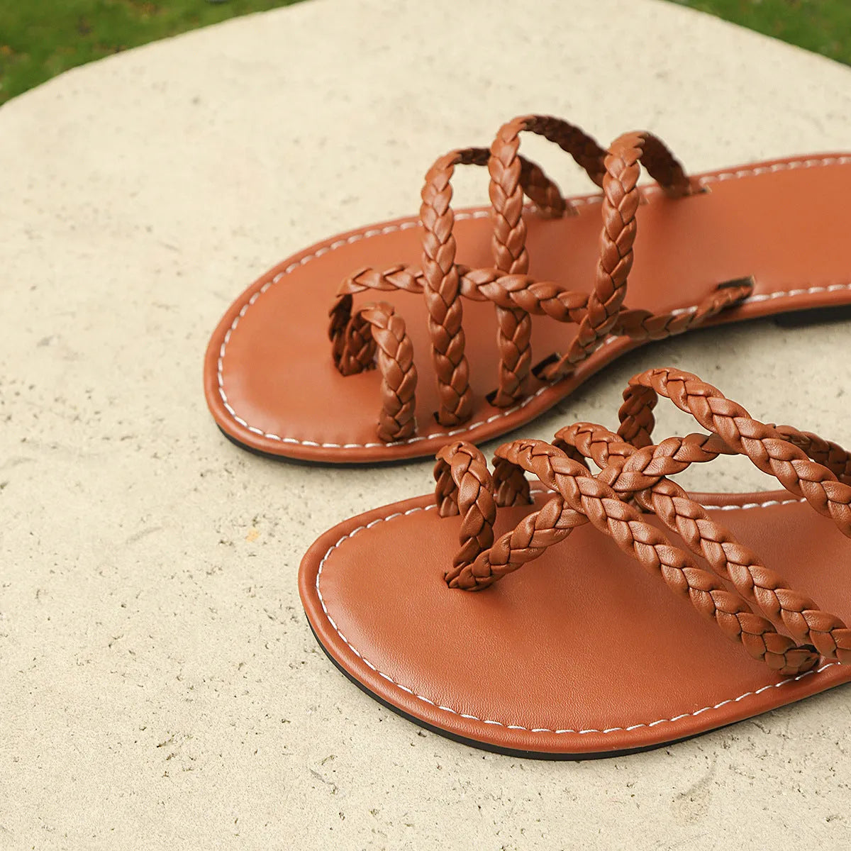 Womens woven Roman sandals with clip toe and flat rubber sole, in white, black, or brown.