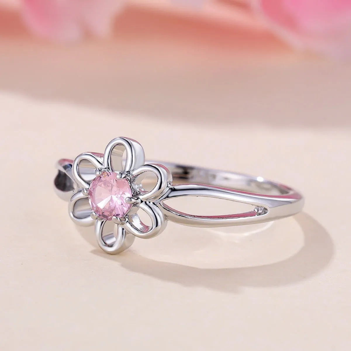 Close-up of a women's hollowed flower ring with a platinum pink diamond electroplated finish.