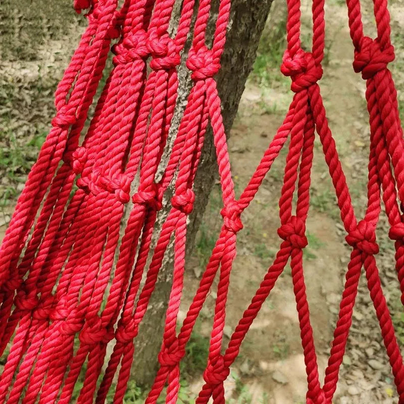 Outdoor nylon rope mesh hammock hanging between two trees showing mesh pattern and included tying ropes