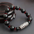 Black agate dzi bead bracelet with geometric beads and hand-woven construction