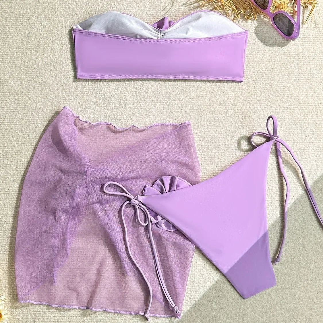 Women's pink tube top swimsuit with a large 3D flower tie, matching pants, and a skirt laid flat.