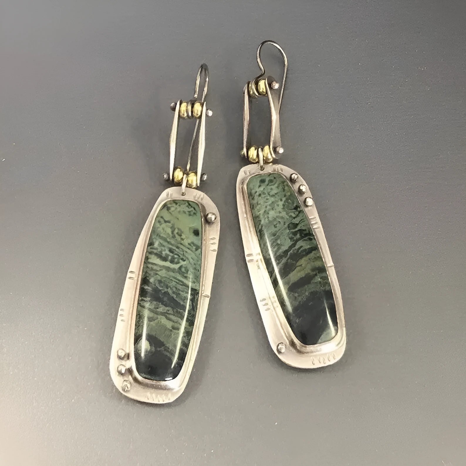 Geometric alloy earrings with a white and grey marble pattern on a simple background.