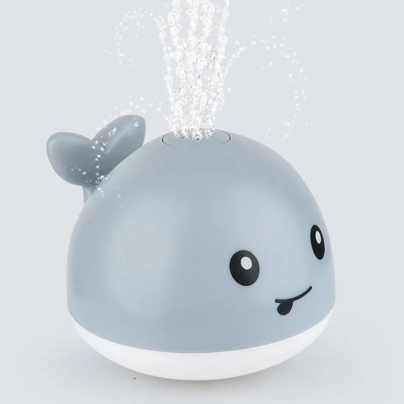 Electric whale bath toy with automatic water spray and flashing lights on a base