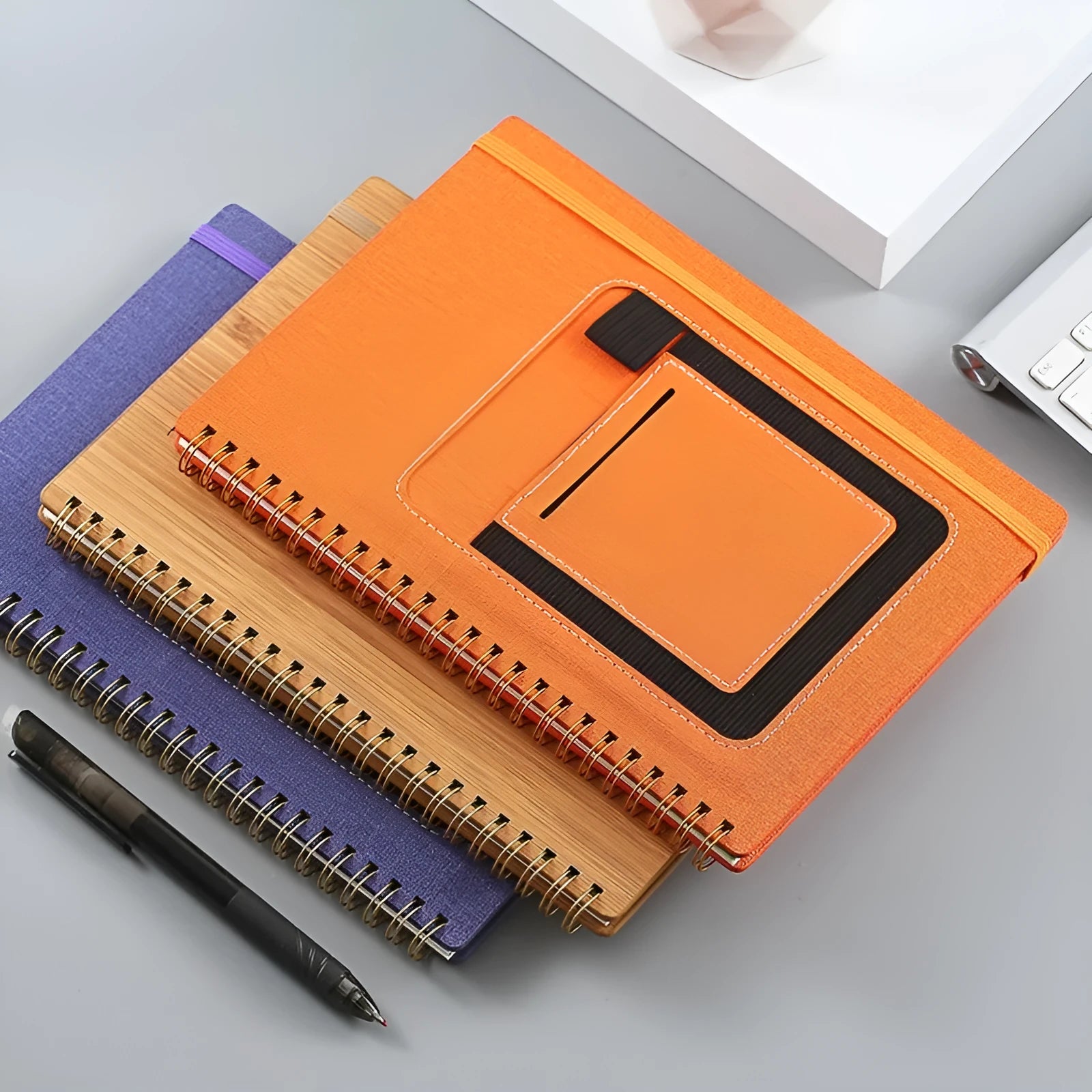 Erasable coil notebook with customisable cover options, shown with dedicated pen on stone paper.