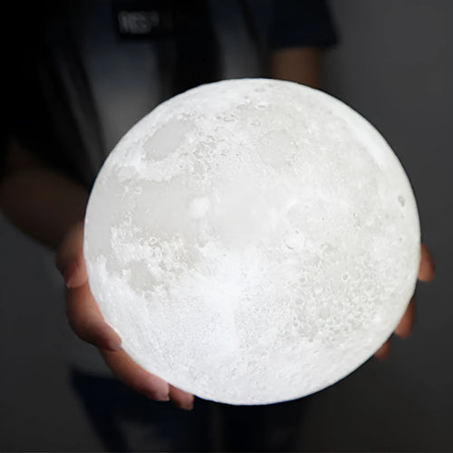 3D printed moon lamp glowing on a wooden stand with touch ring at base