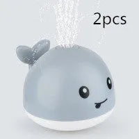 Electric whale bath toy with automatic water spray and flashing lights on a base