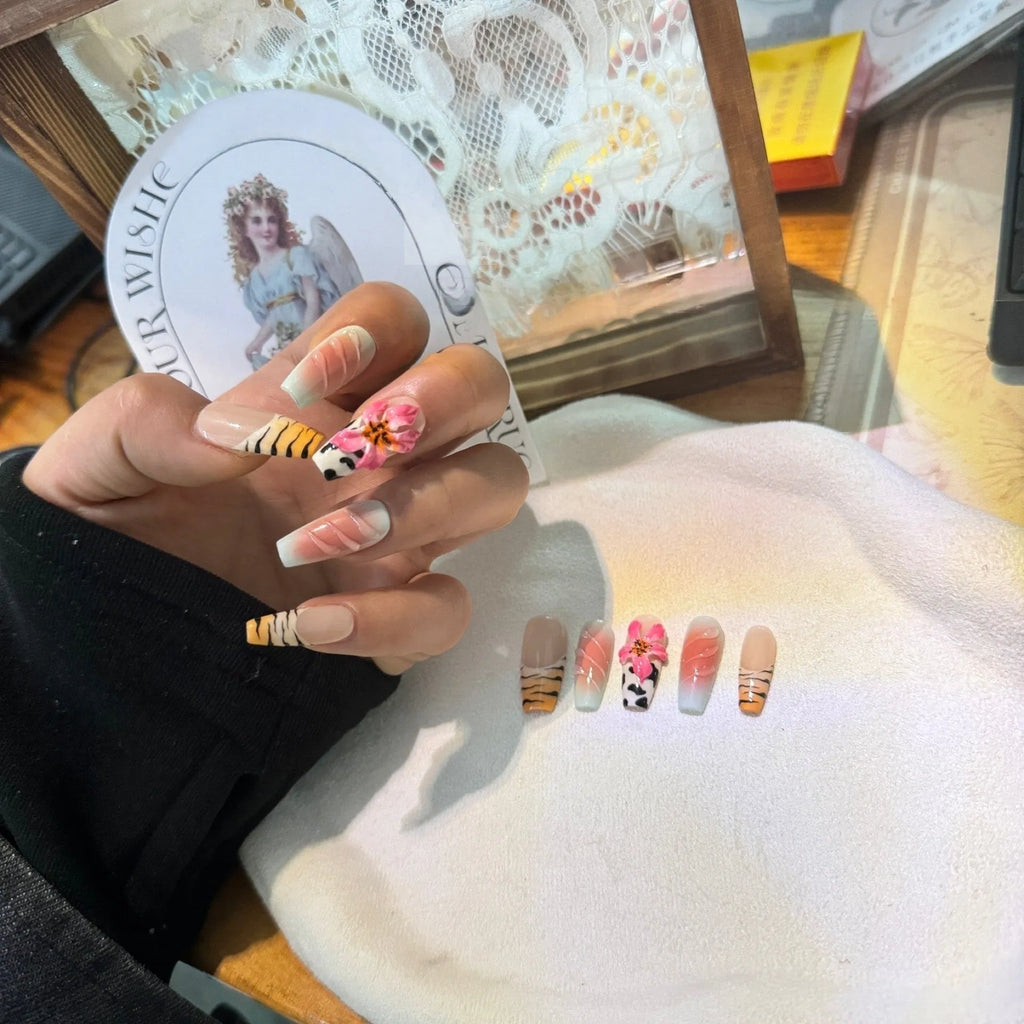 Close-up of zebra pattern artificial nails with embossed lily flower and leopard print designs, shown in long wear-resistant style.