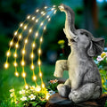 Grey resin elephant garden statue with white LED string lights wrapped around its body.