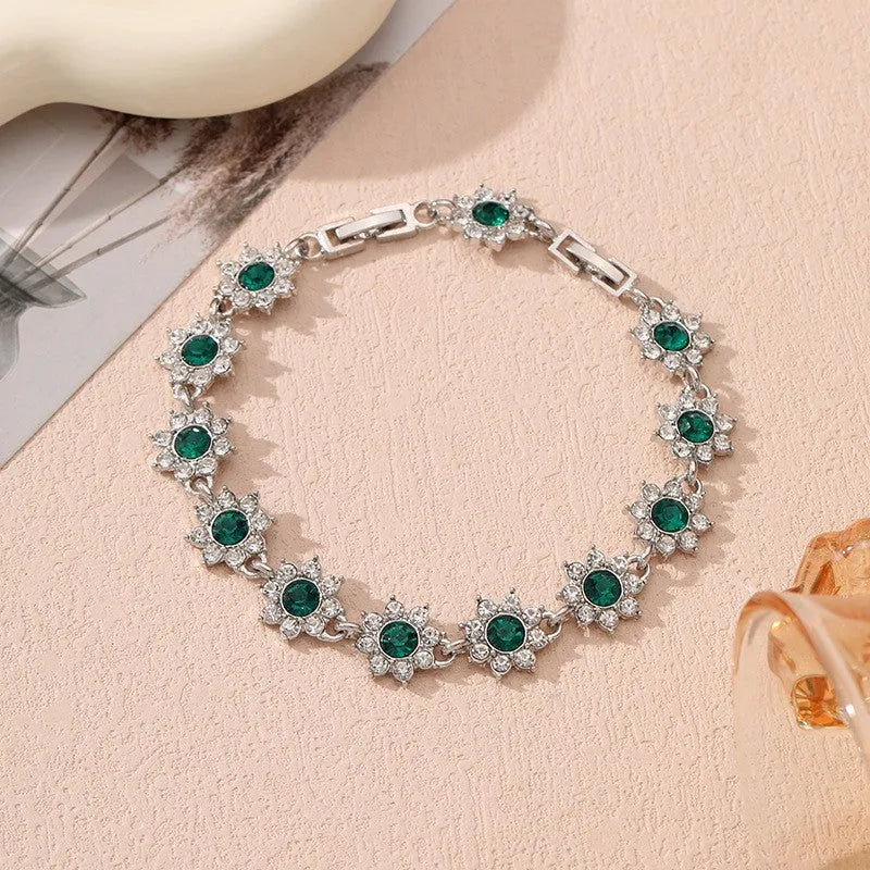 Electroplated zinc alloy bracelet with flower-shaped coloured gems in gold or silver tone.