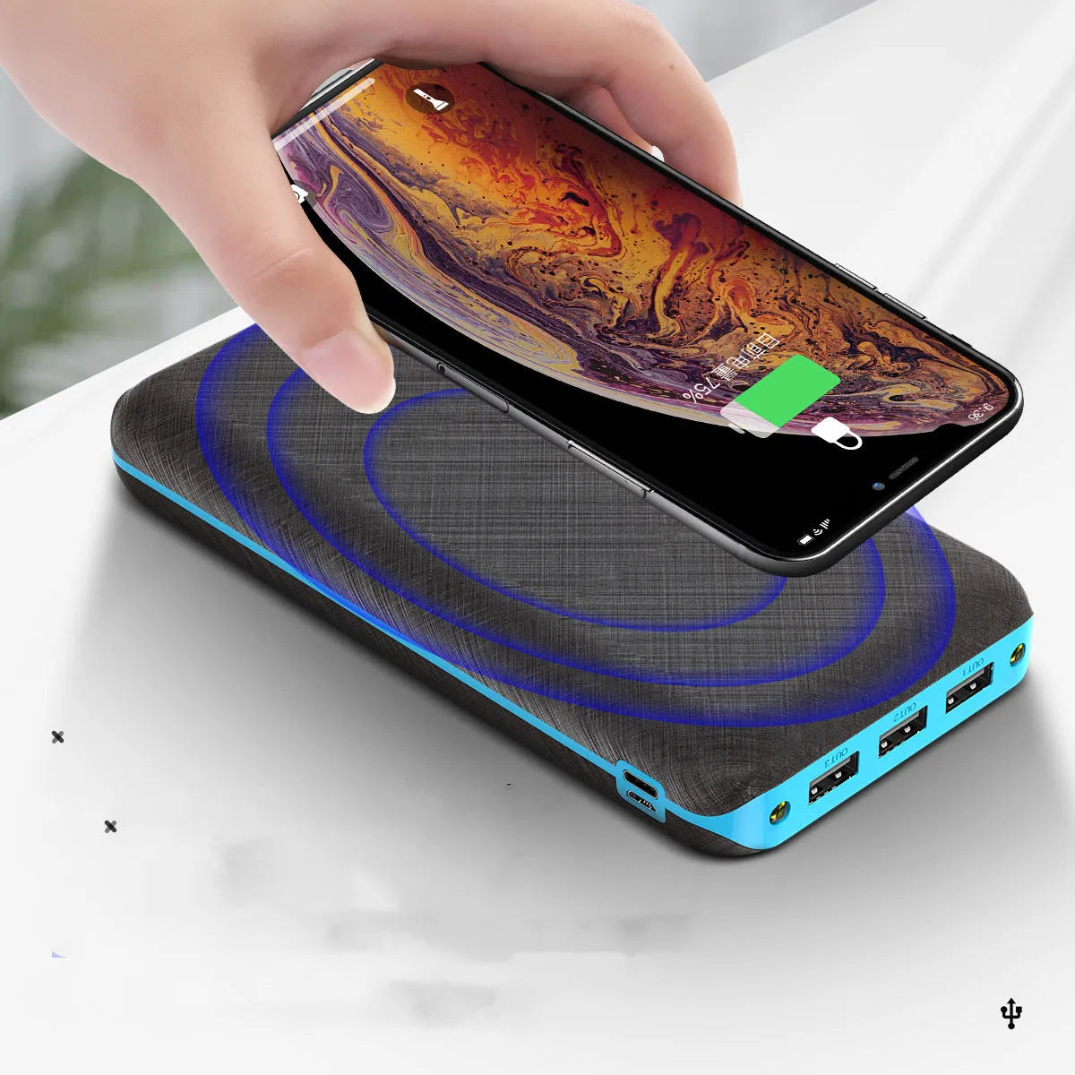 Black portable solar power bank with wireless charging pad and three USB ports on a wooden surface.