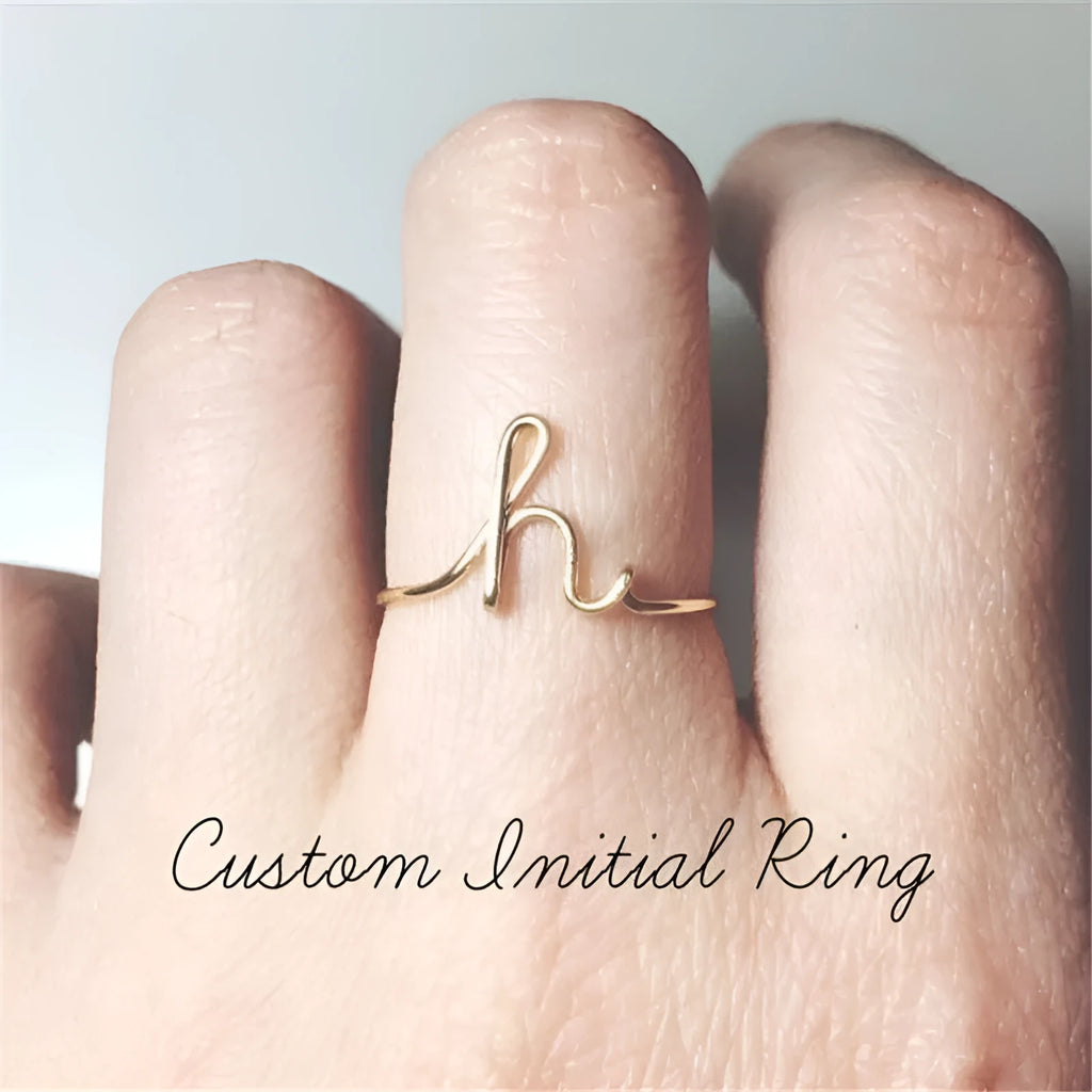 Gold coloured unisex alloy initial ring with letter A geometric shape on a flat surface