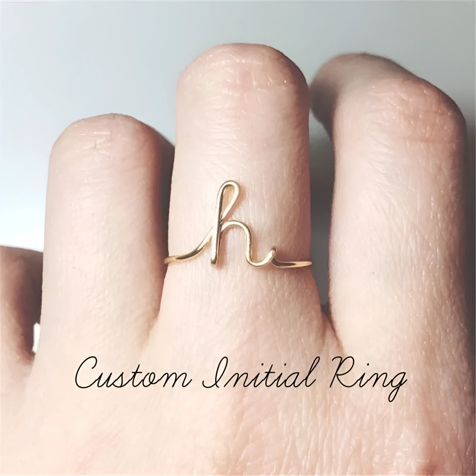 Gold coloured unisex alloy initial ring with letter A geometric shape on a flat surface