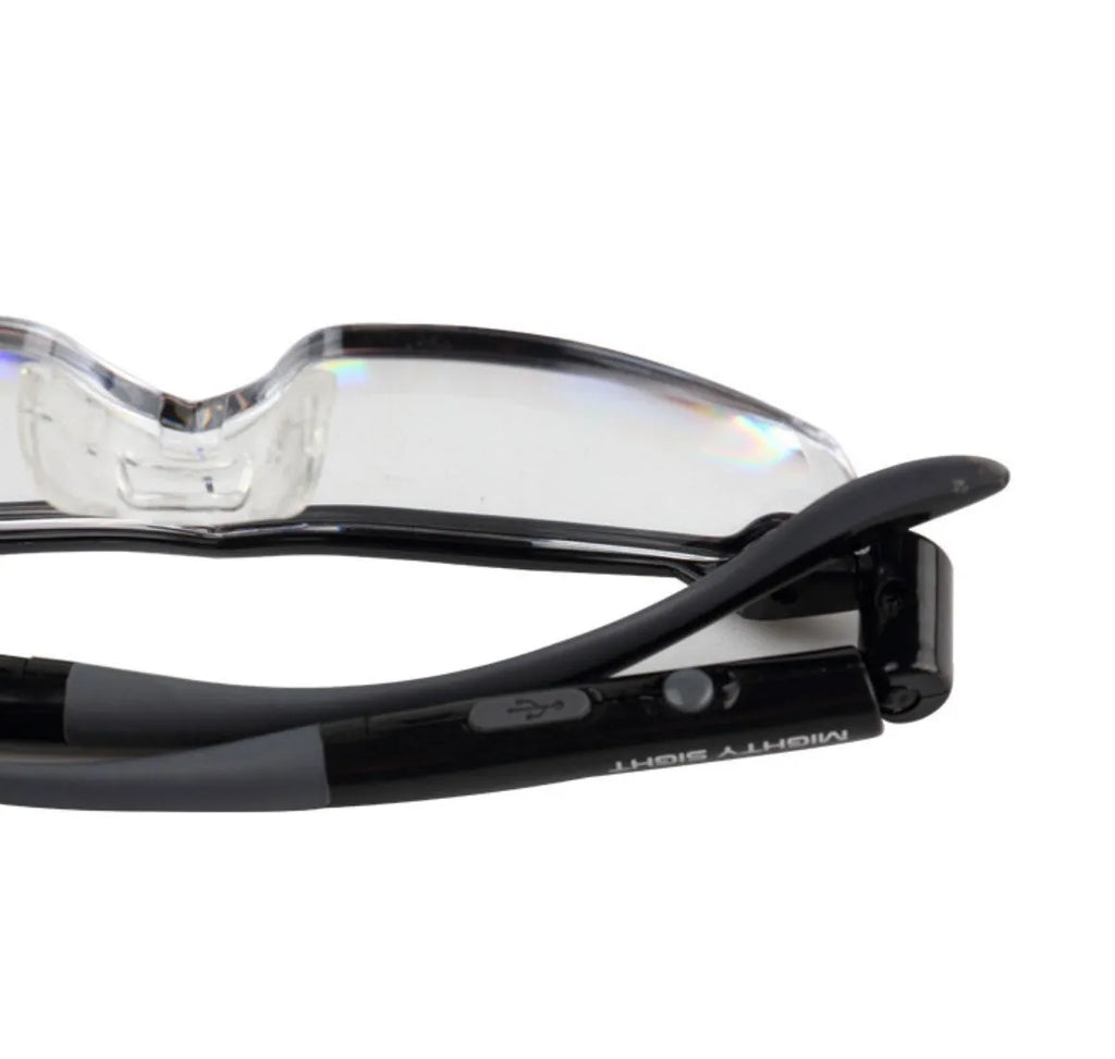 Transparent black USB LED reading glasses with scheduled lighting mode on desk