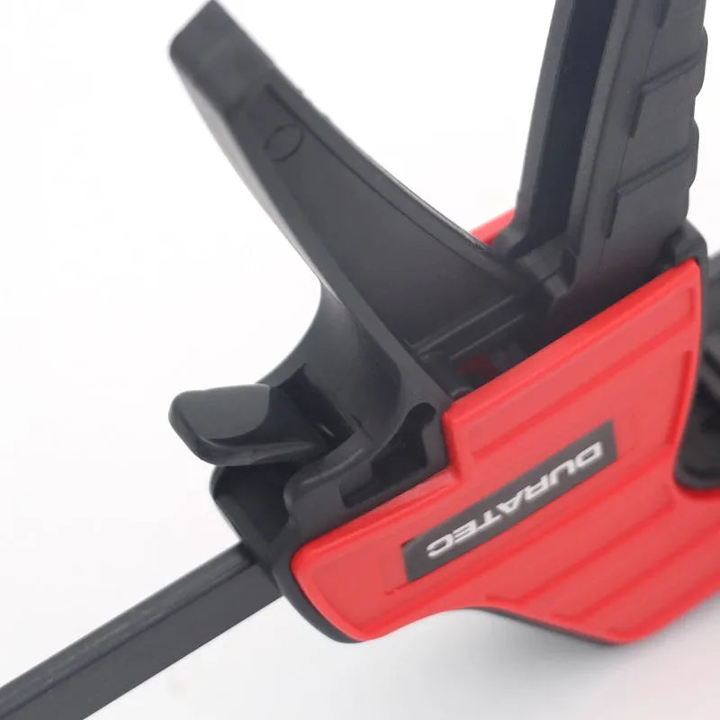 Black plastic woodworking clamp with quick-release lever and rubber grip pads in multiple sizes