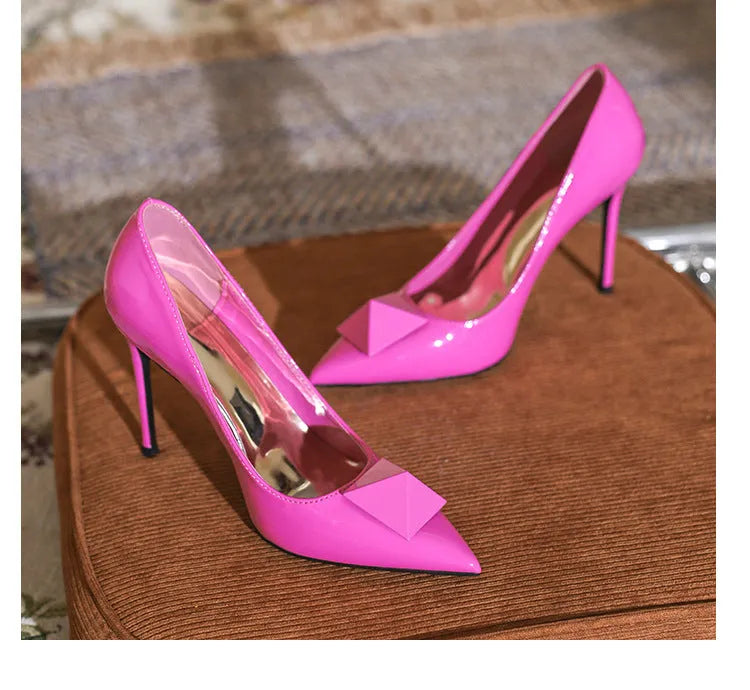 Pink women's pointed toe stiletto high heels with a rivet buckle on the ankle strap.