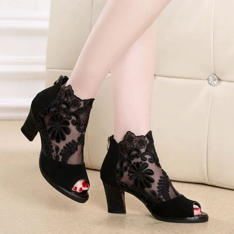 Women's black lace-up gladiator sandals with a square high heel and decorative floral detail on the peep toe