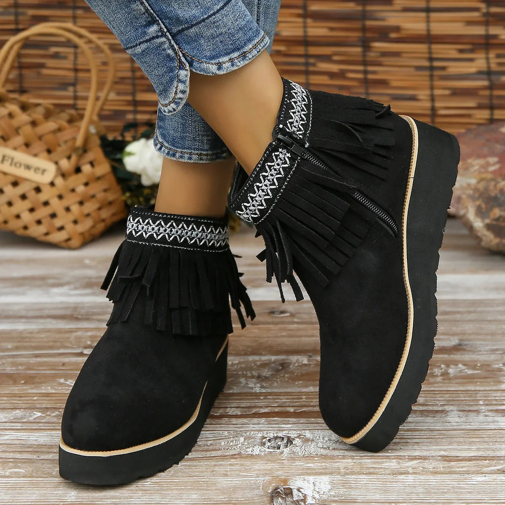 Women's suede ankle boot with wedge rubber sole, side zip, and tassel detail in dark brown.