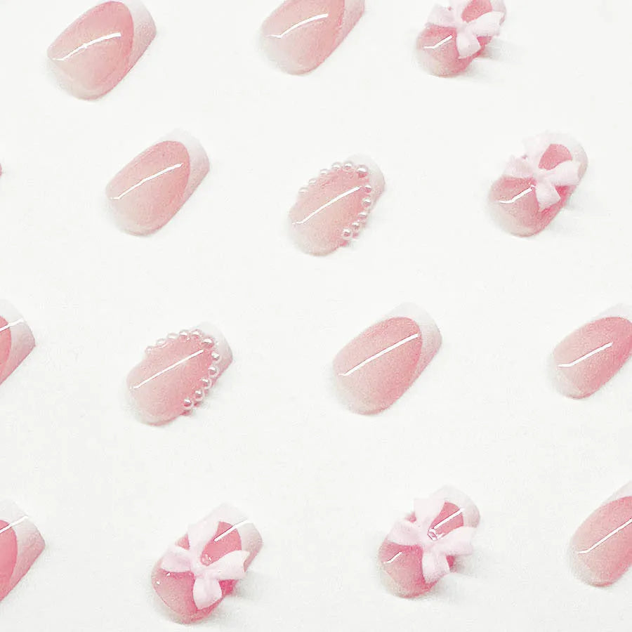 Short white French false nails with bow and tulip designs on a European square shape.