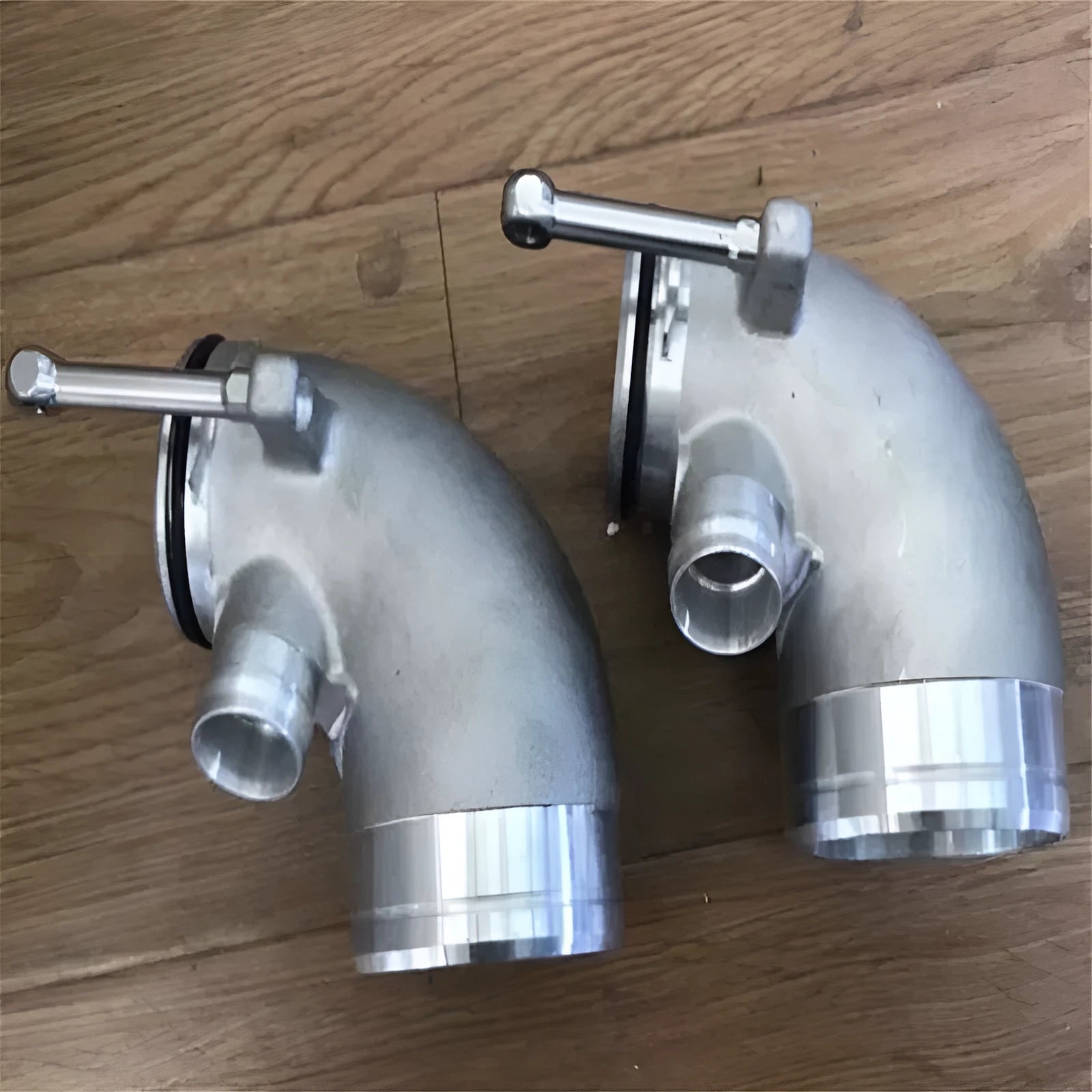 Black aluminium alloy 90 degree turbocharger elbow tube for lateral engine mounting.