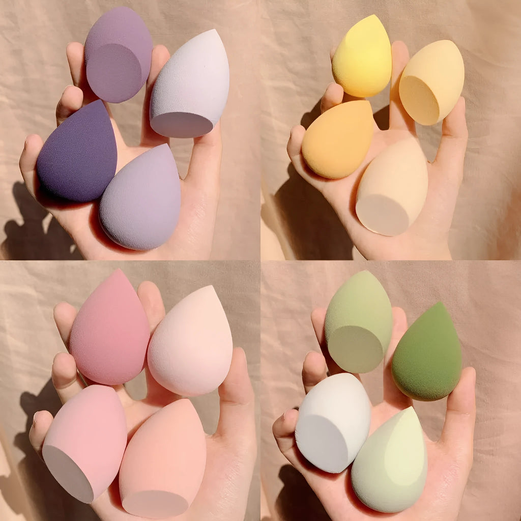 Set of four colourful synthetic makeup beauty egg sponges in grape, mango, mint, and peach, each roughly 6cm cubed.