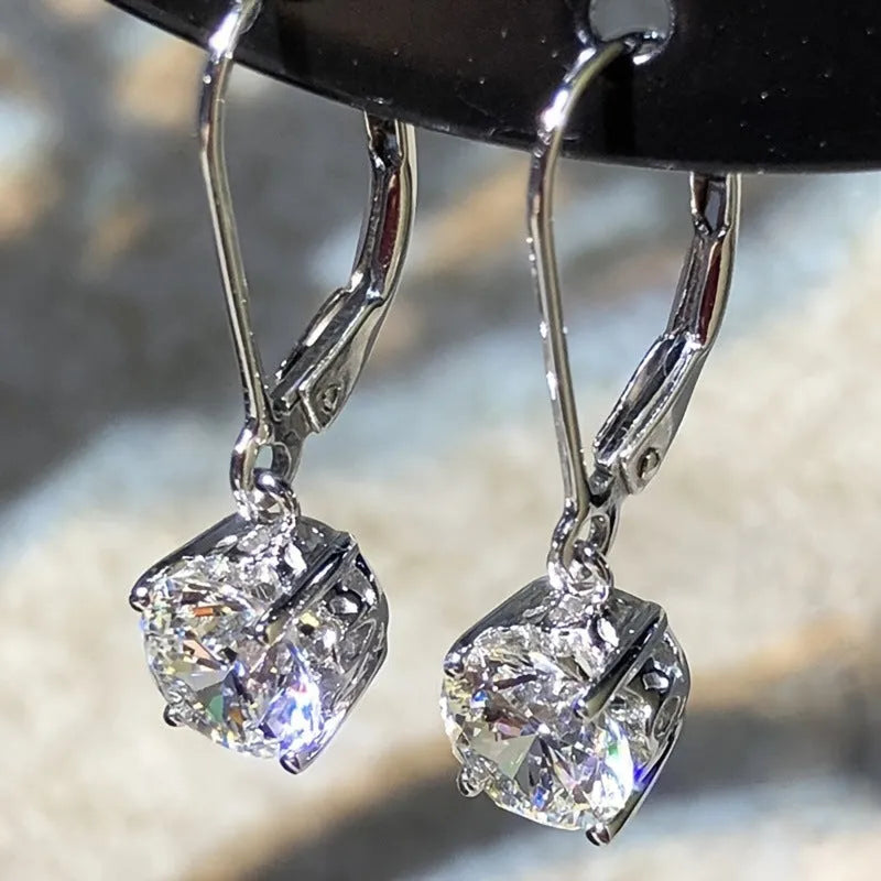 Silver colour zircon earrings with genuine stones and secure metal fastening on a white background