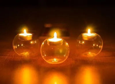 Handmade clear hollow glass sphere candle holder with tea light inside on wooden table