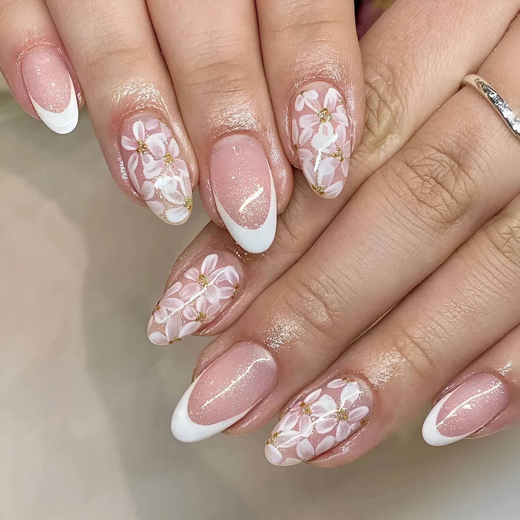 Short almond French manicure press-on nails with pink glitter finish and floral designs