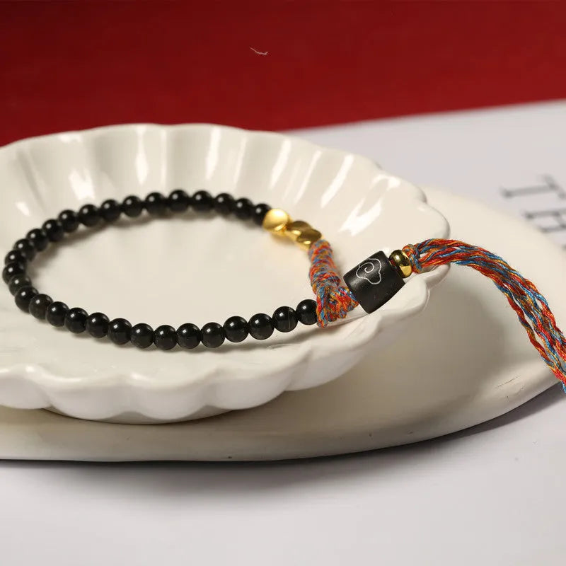 Hand-woven obsidian bracelet with dark beads showing woven texture and adjustable 15.5-16cm length