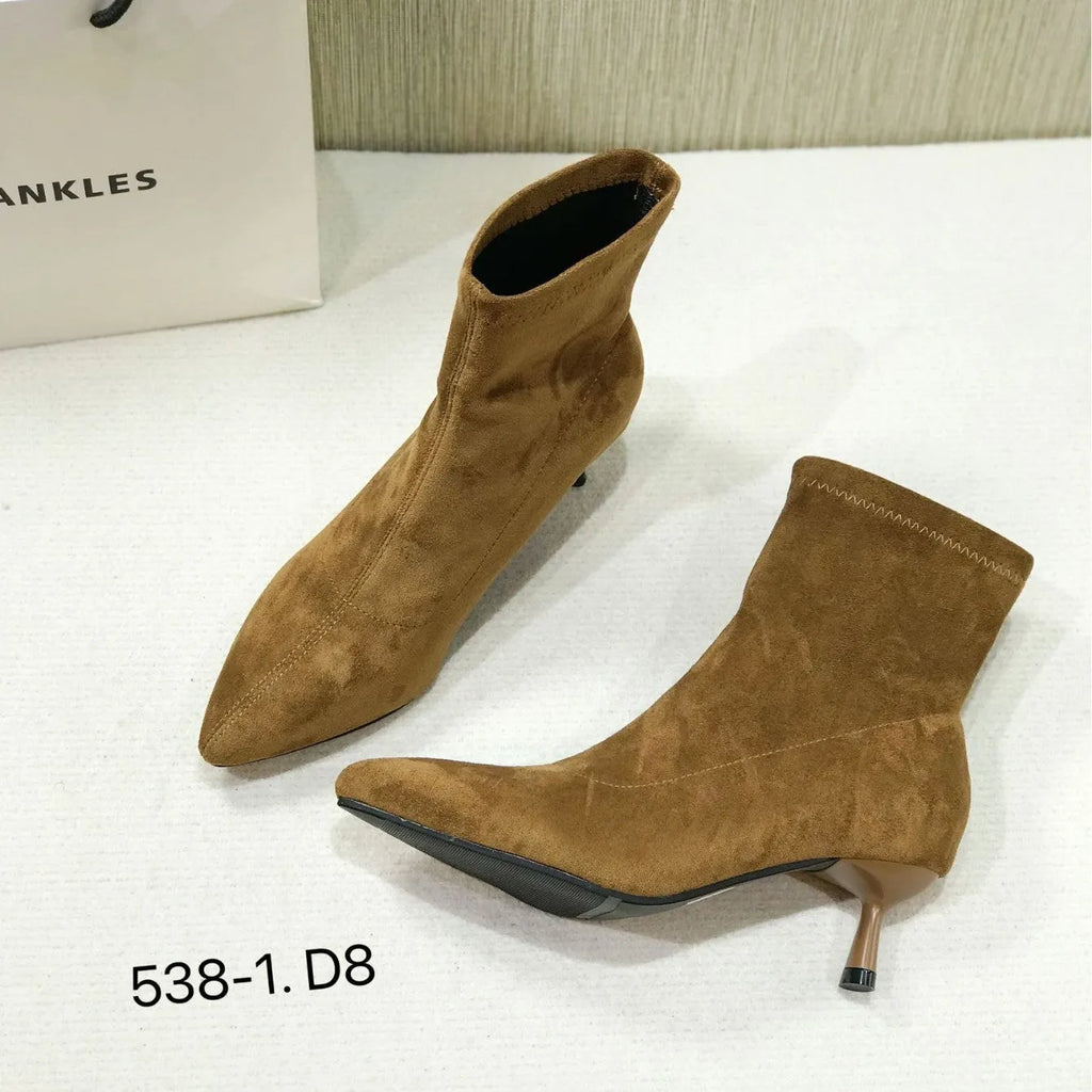 Black pointed toe ankle boots with a stiletto heel on a plain background.