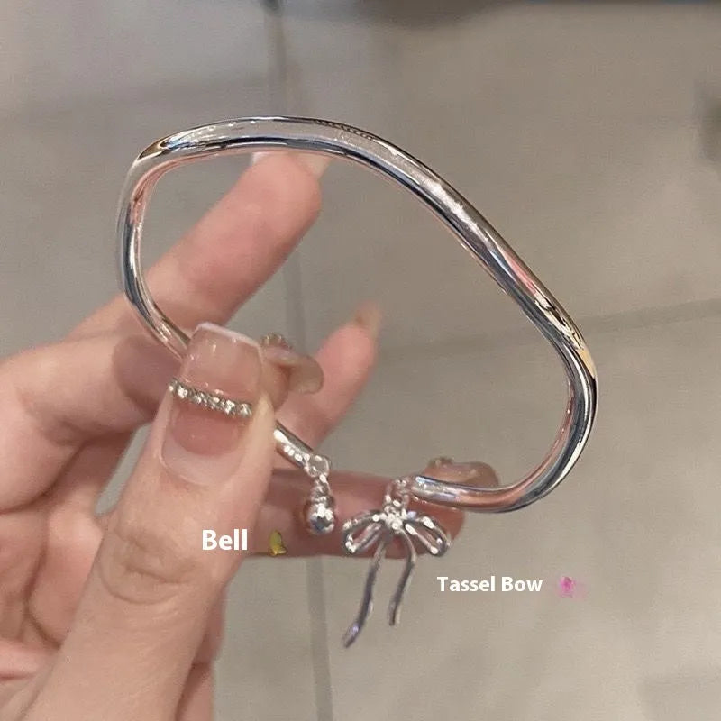 Silver adjustable bracelet with a detailed bow charm and bell opening.