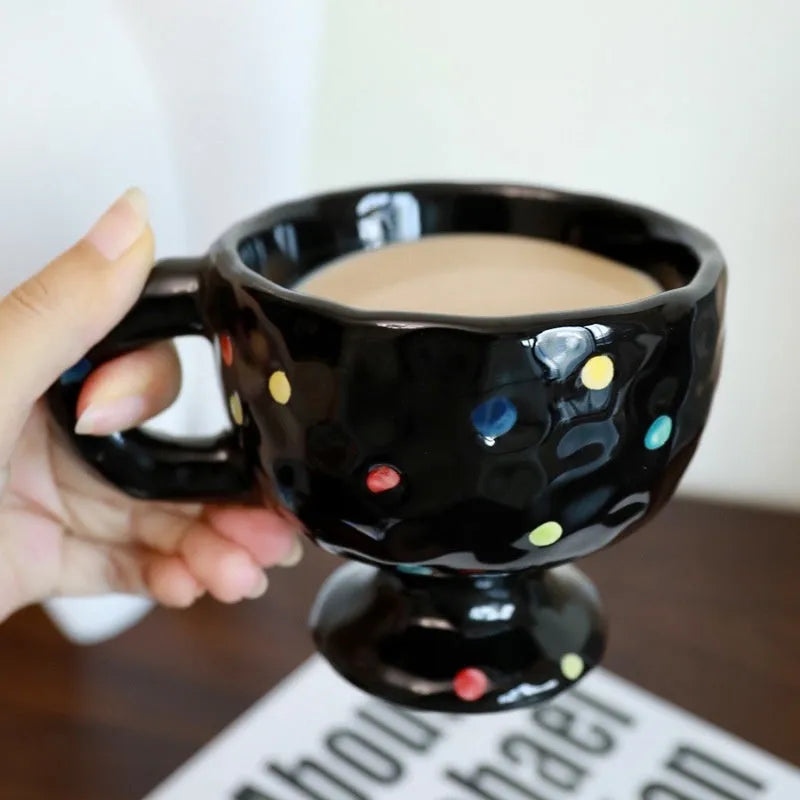 Hand-pinched irregular shaped ceramic mug in a solid colour, shown on a table.