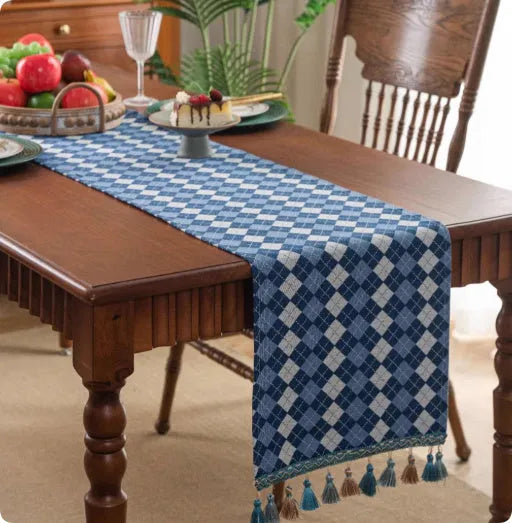 Long European-style retro table runner with decorative tassels in a floral design on a wooden table.