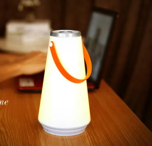 White rechargeable LED bedside table lamp with USB cable on a wooden surface.