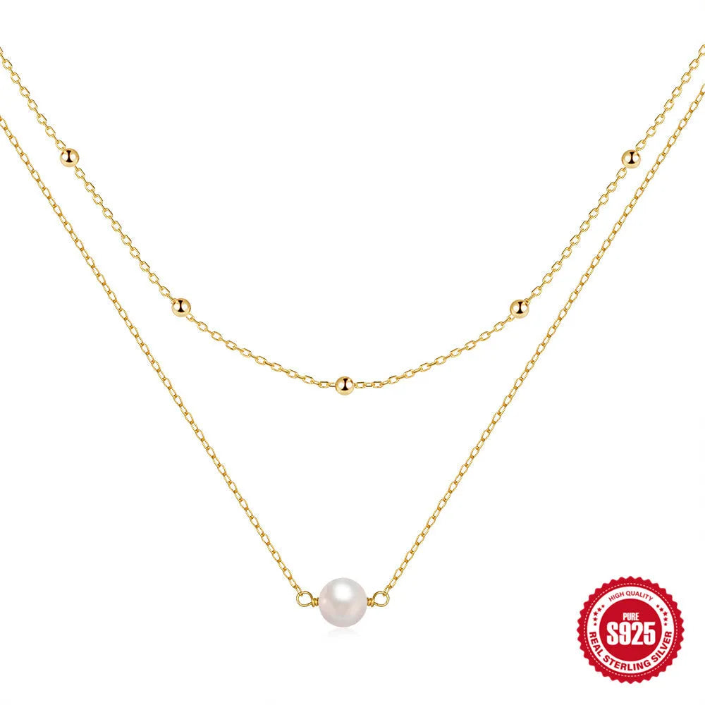 Close-up of a sterling silver double layer necklace with twin pearls on a ball bead chain, shown in gold tone.