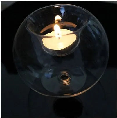 Handmade clear hollow glass sphere candle holder with tea light inside on wooden table