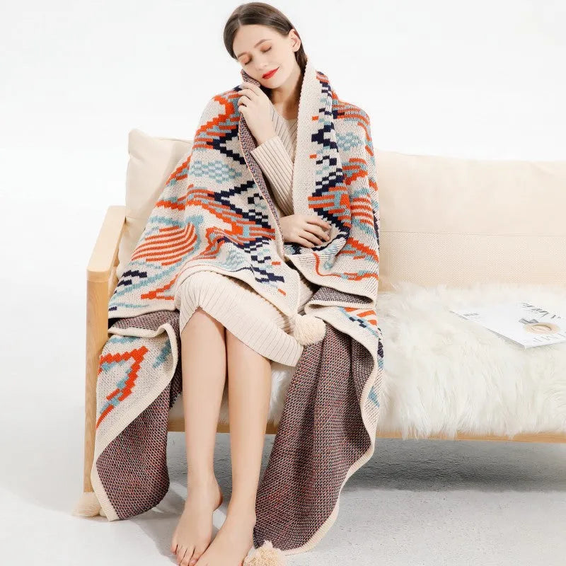 Large beige acrylic sofa blanket with tassel fringe draped over a grey sofa