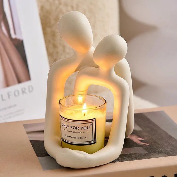 Modern loving couple resin statue in milky white or gold on a bookshelf.