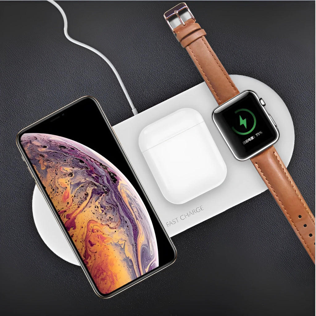 White three-in-one wireless charging stand holding an iPhone, Apple Watch, and AirPods on a wooden desk.