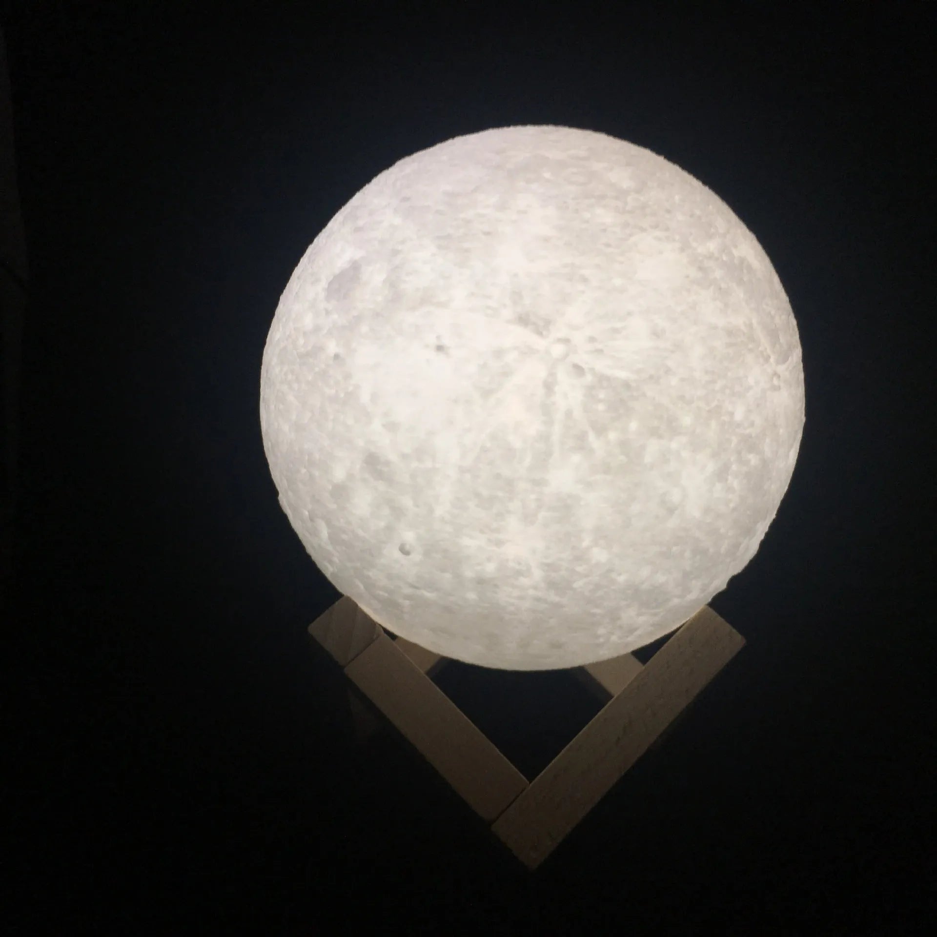3D printed moon lamp glowing on a wooden stand with touch ring at base