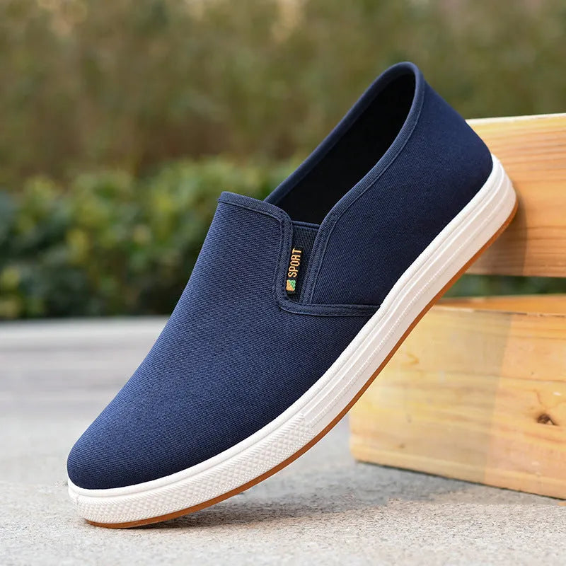 Men's black low-top canvas slip-on shoes with round toe and shallow mouth design on a white background.