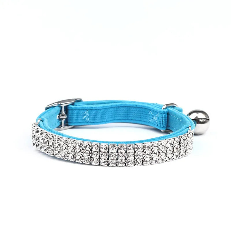 Close-up of a soft red velvet cat collar with a line of sparkling rhinestones and an adjustable buckle.