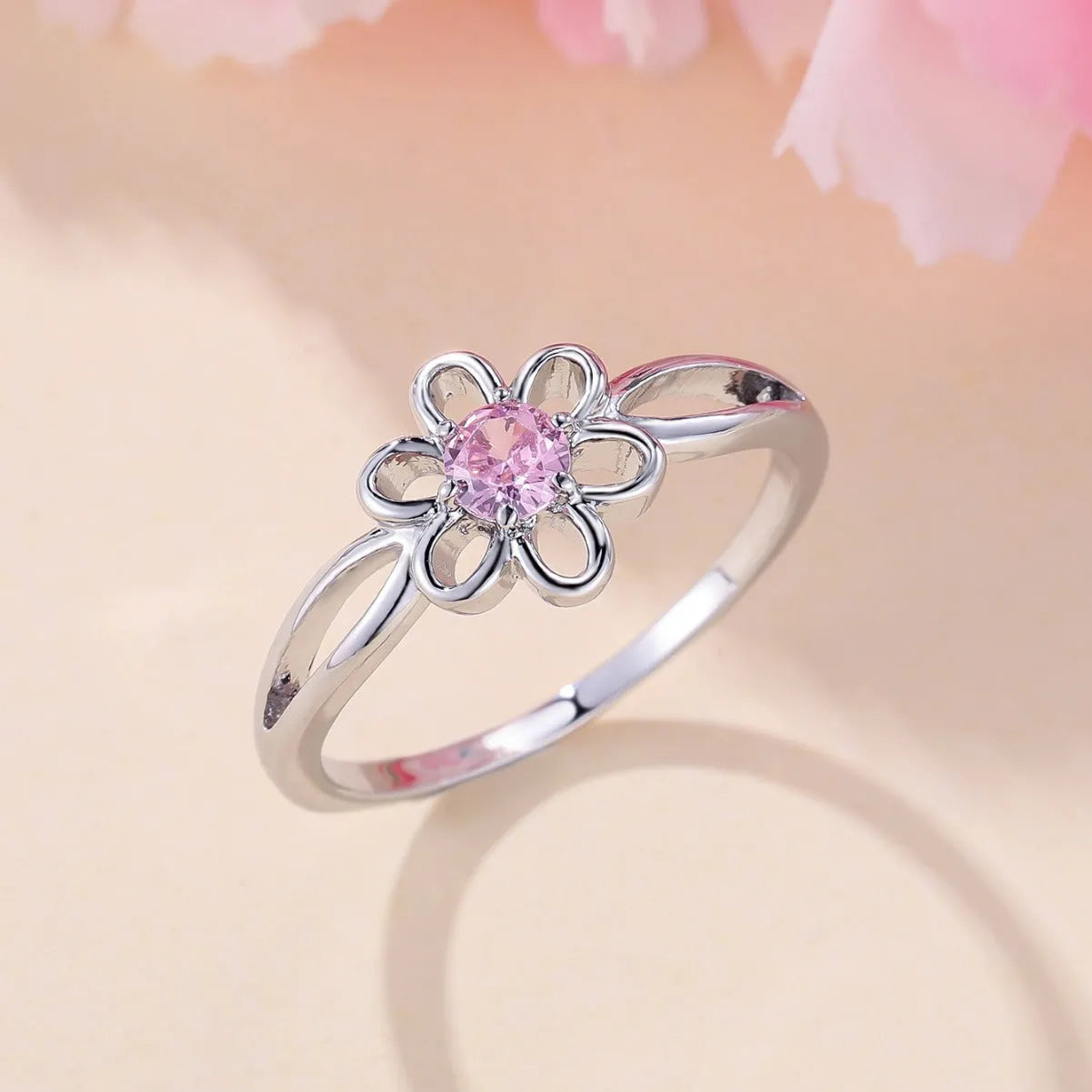 Close-up of a women's hollowed flower ring with a platinum pink diamond electroplated finish.