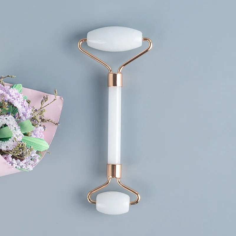 White jade double-headed facial roller and gua sha scraping board set on a neutral background.